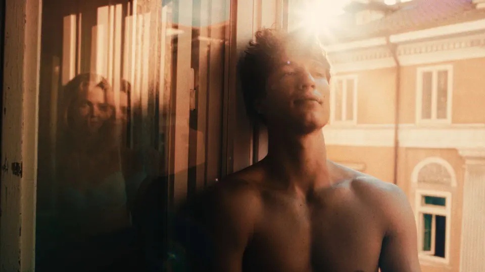 Homem encostado na janela com luz de fim de tarde, já com color grading